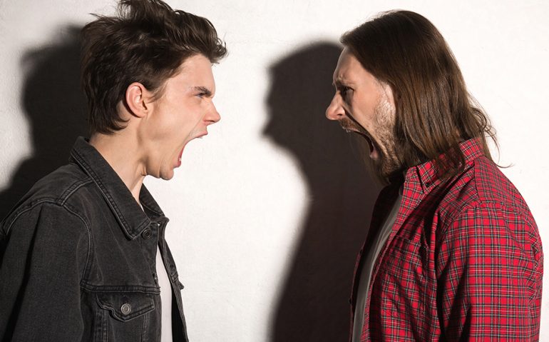 Image of screaming angry young hipsters men standing over gray background.